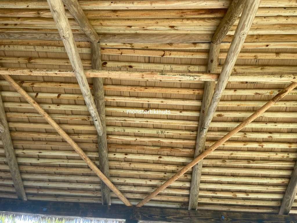 Close-up of folded synthetic thatch between wooden roof battens