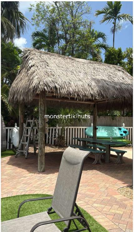 Tiki hut on herringbone brick patio with tropical landscaping